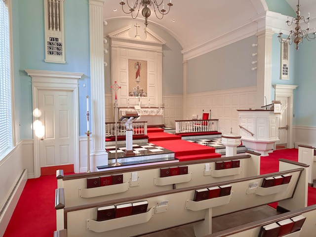 Historic sanctuary with white pews and red carpet