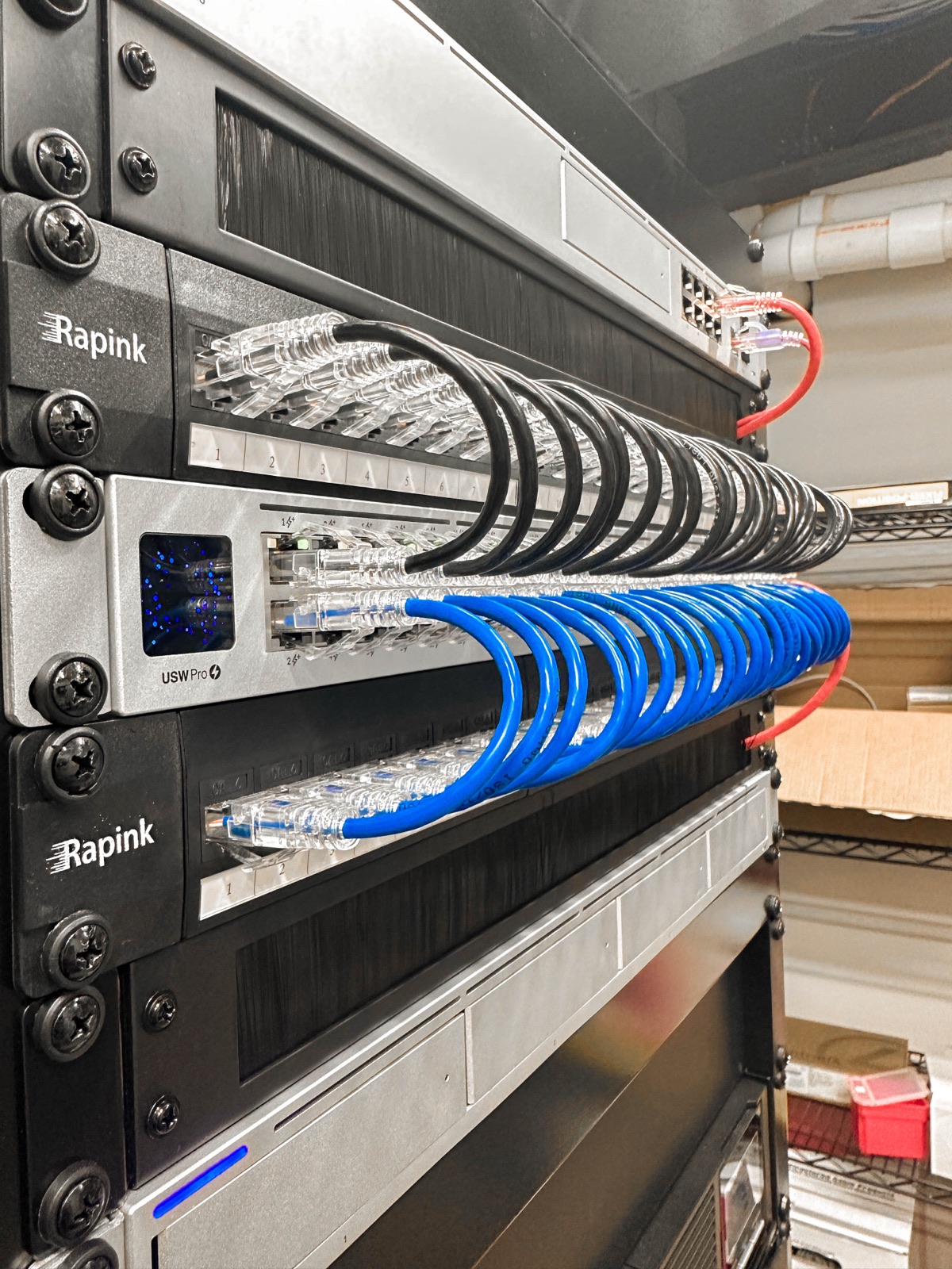 Wall rack with patch panel and switch, blue patch cables dressed