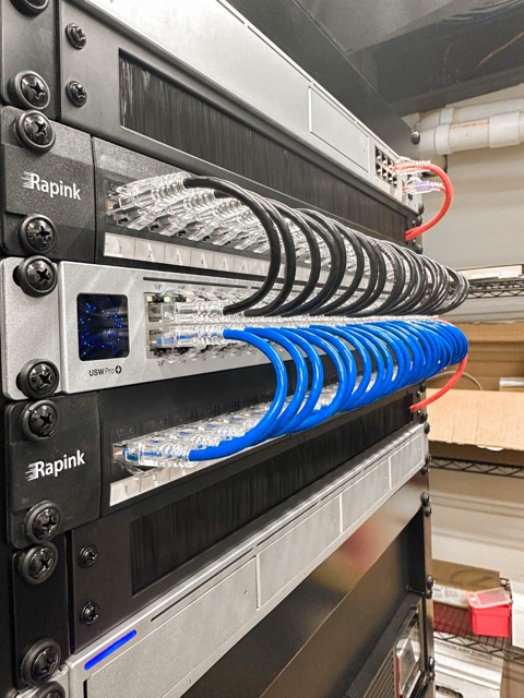 Wall rack with patch panel and switch, blue patch cables dressed