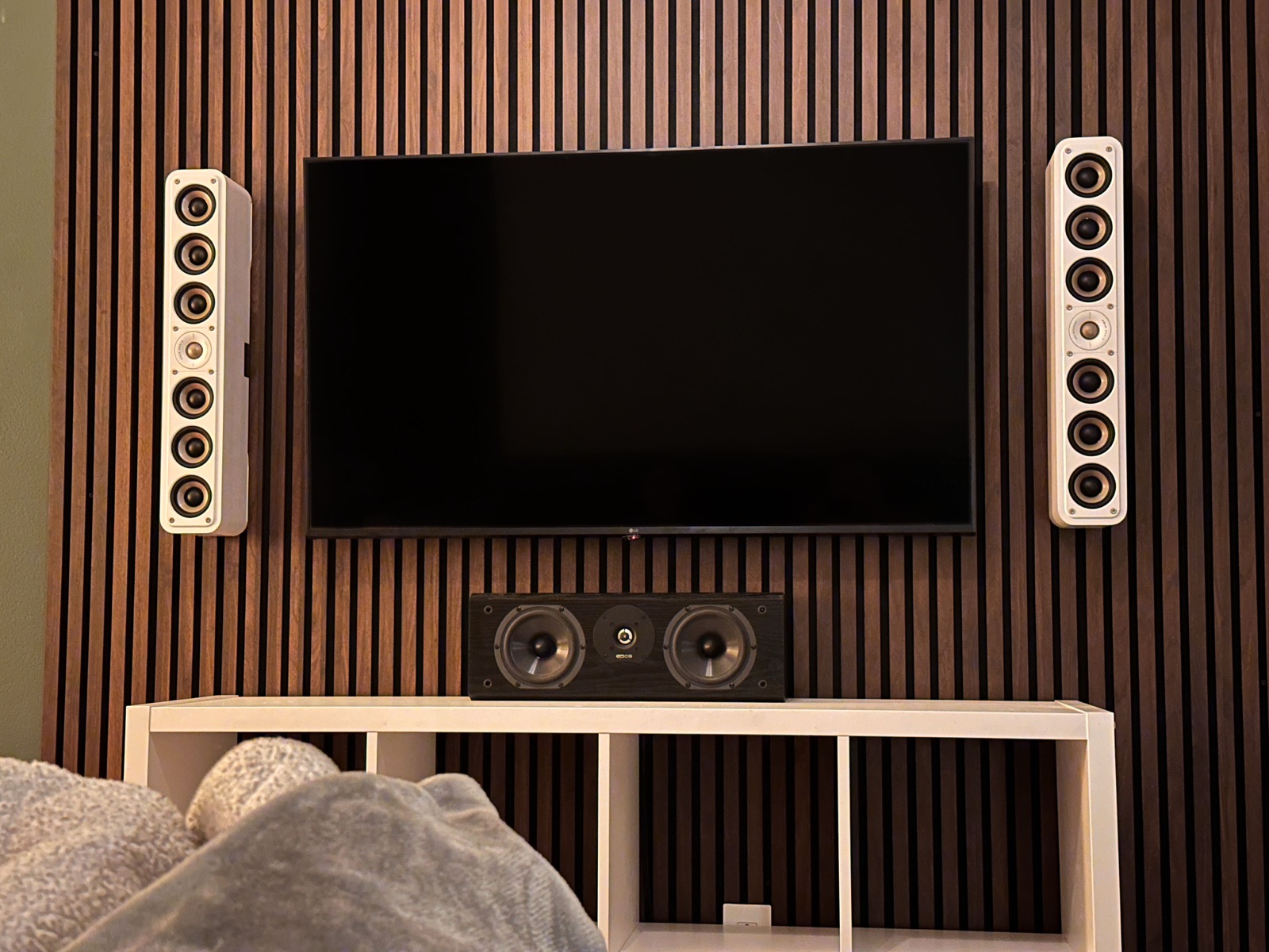 Slat wall with mounted TV, in-wall speakers, and center channel