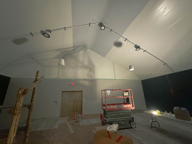 Vaulted office room with ceiling speakers and track lighting